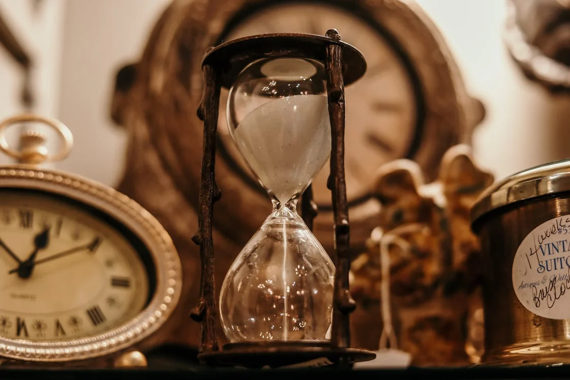 Close-up of a vintage hourglass and clock, representing time management